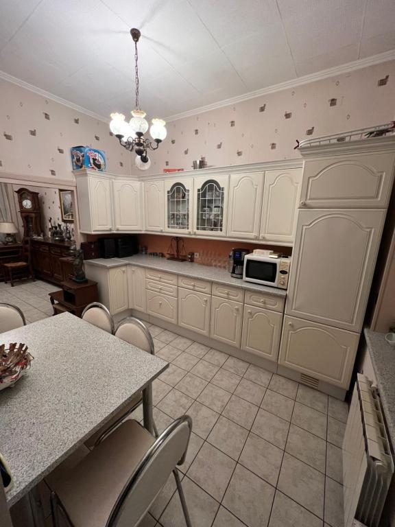 une cuisine avec des armoires blanches et une table avec des chaises dans l'établissement Maison 3 chambres, à Roubaix