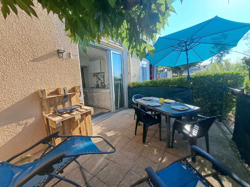 un patio avec une table, des chaises et un parasol dans l'établissement Apt RDC avec accès direct plage, grande terrasse, cuisine équipée, PARKING - FR-1-326-837, à Marseillan