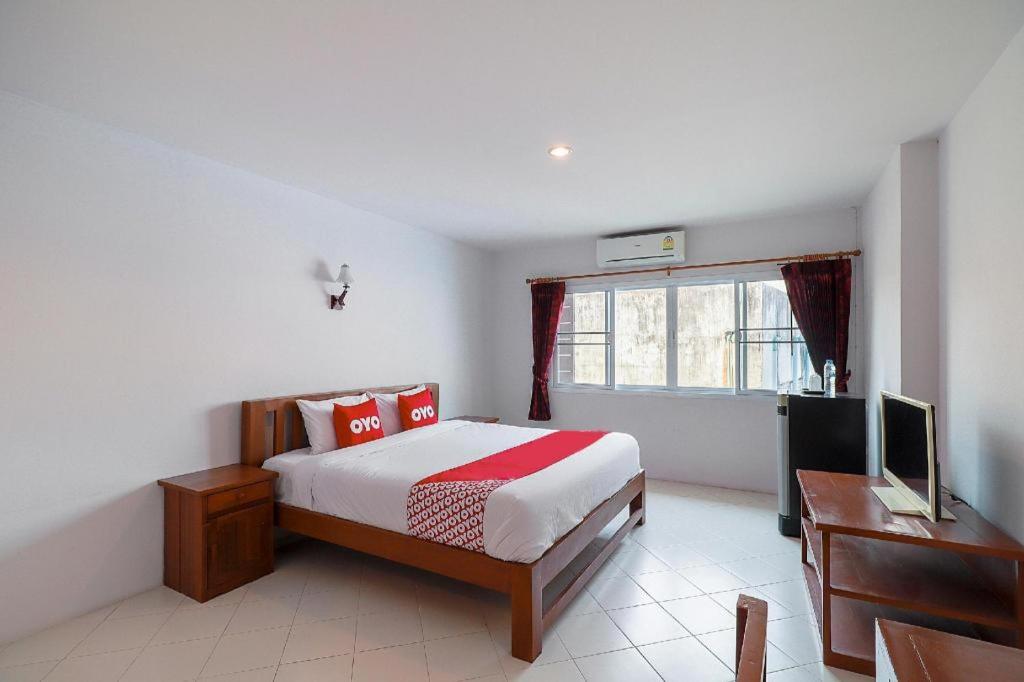 Un dormitorio con cama, escritorio y televisión. en OYO 794 Nice Mum Lodge, en Chiang Mai