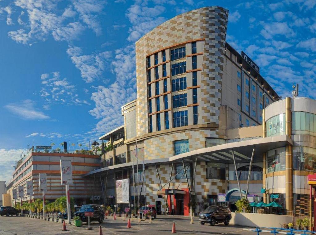 a large building on a street with cars parked in front at Grand Qin Hotel Syariah in Banjarbaru