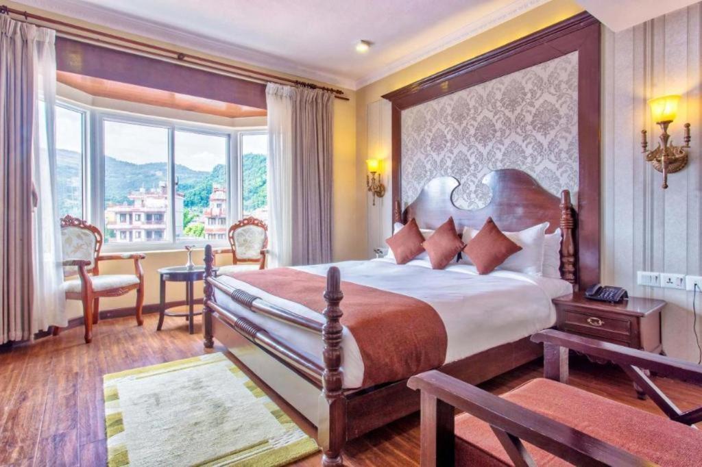 Un dormitorio con una cama grande y una ventana grande. en Da Yatra Courtyard Hotel & Resort, en Pokhara