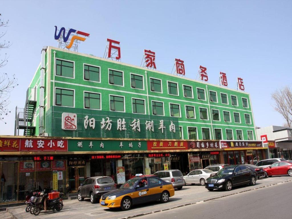 un bâtiment vert avec des écritures chinoises dessus dans une rue dans l'établissement Beijing Wanjia Traders Hotel, à Pékin