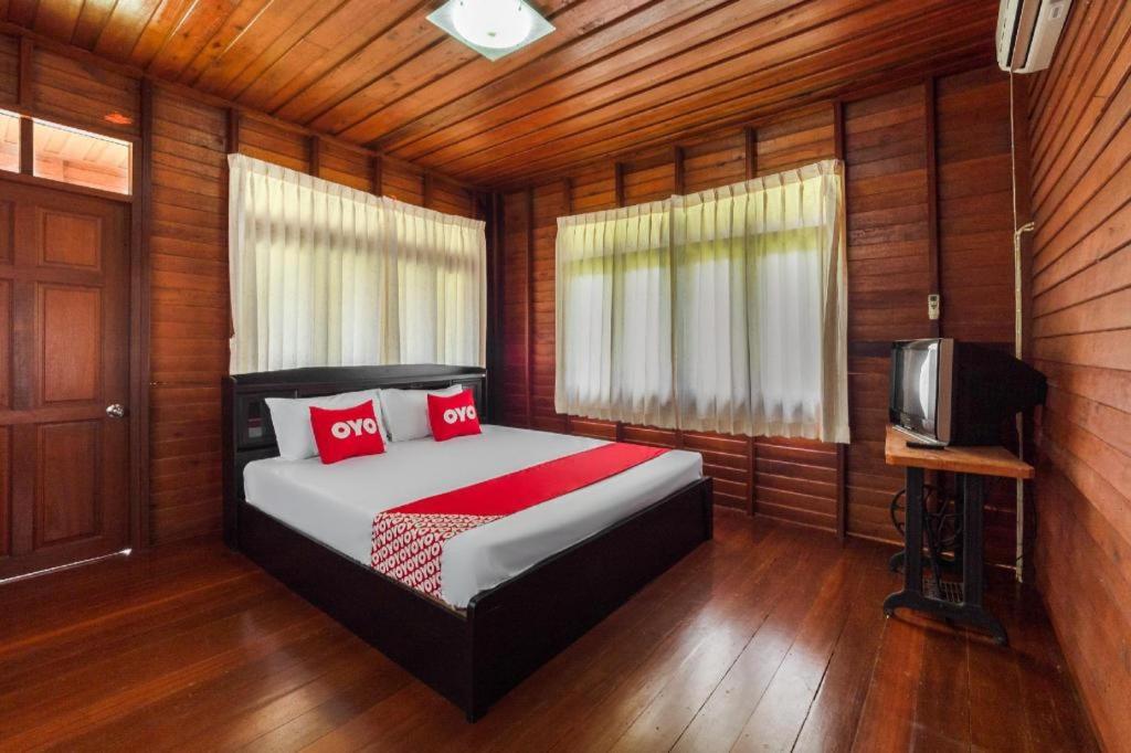 - une chambre avec un lit doté d'oreillers rouges et une télévision dans l'établissement OYO 1143 Phet Luran Thai Resort Kohchang, à Ko Chang