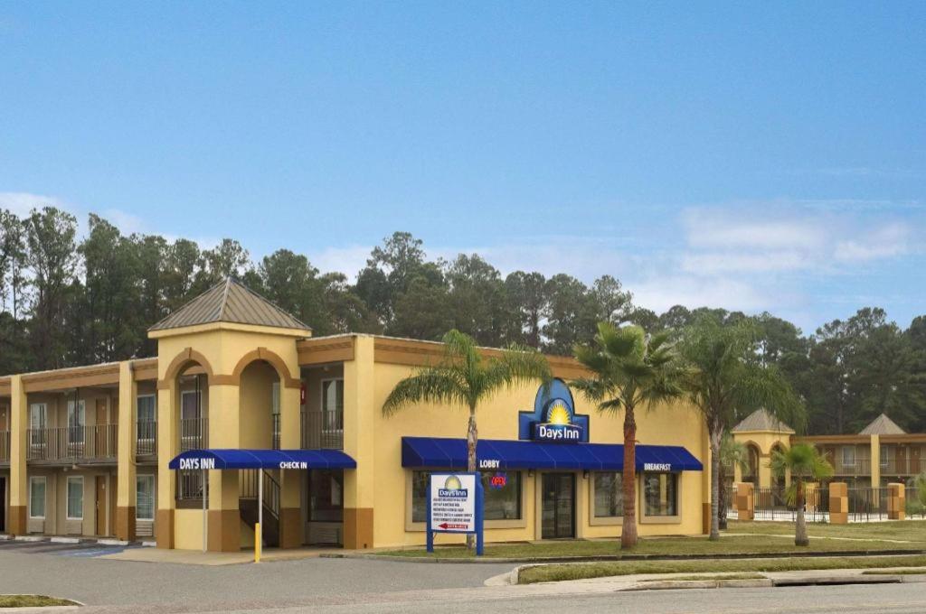 a yellow building with a sign in front of it at Days Inn by Wyndham Brunswick/St. Simons Area in Glynn Heights