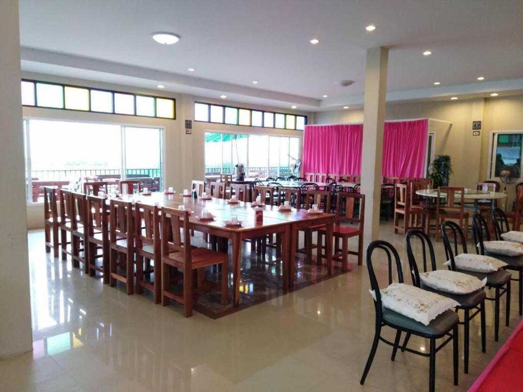een restaurant met een grote houten tafel en stoelen bij Hadthong Resort in Ban Hat Khai Tao