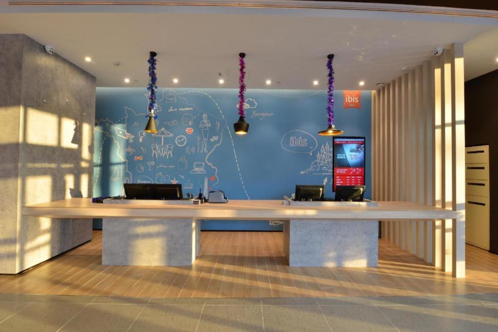 a large desk in a room with a blue wall at Ibis Harbin Normal University in Harbin