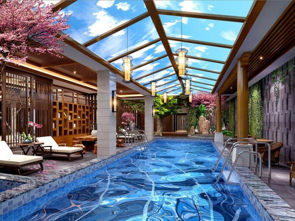 einen Pool in einem Haus mit Glasdecke in der Unterkunft GreenTree Inn Kunming Baiyun Road Tongde Plaza Branch in Kunming