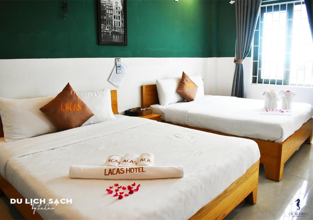 two beds in a hotel room with towels on them at LaCas Hotel Quy Nhon in Quy Nhon