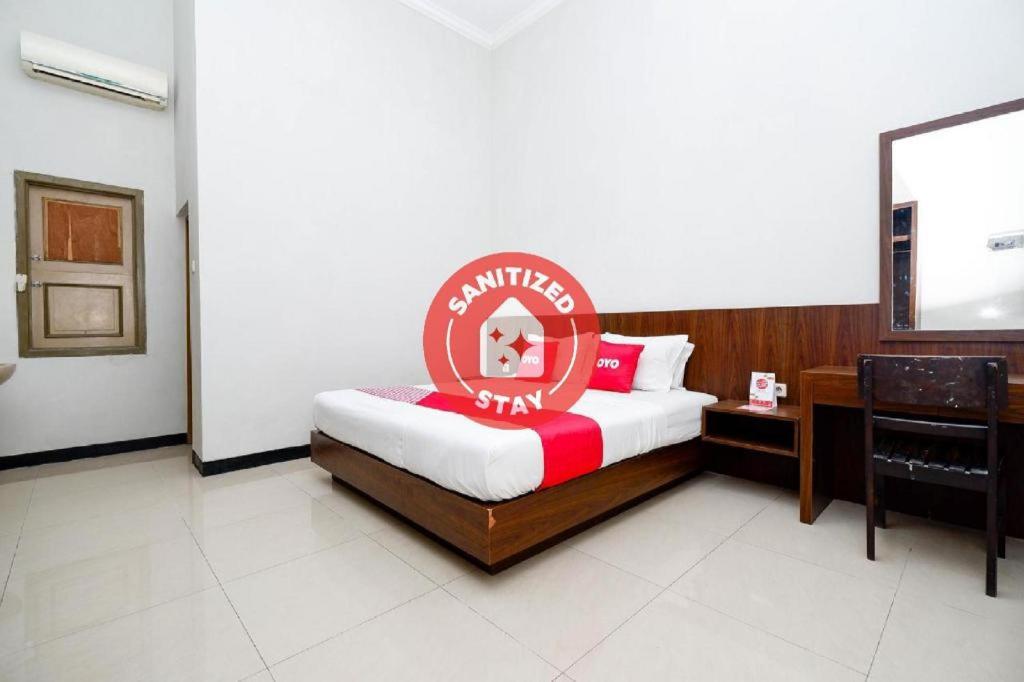 a hotel room with a bed with a sign on it at Super OYO 2436 Hotel Kencana in Tegal
