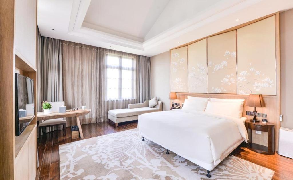 南通市にあるAtour Hotel Nantong Langshan Scenic Areaの大きな白いベッドとリビングルームのある寝室