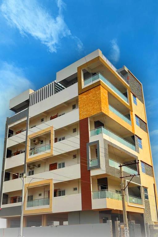 a tall apartment building with a blue sky in the background at Vaga Suites in Tirupati