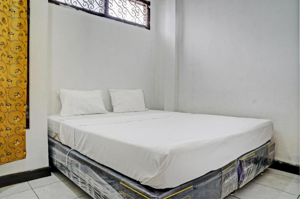 białe łóżko w pokoju z oknem w obiekcie SPOT ON 93475 Garuda Homestay Syariah w mieście Sukabumi