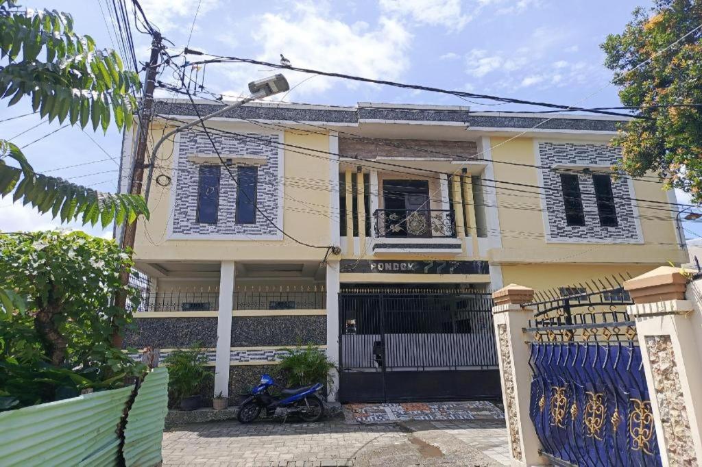 una casa amarilla con contraventanas azules y una puerta en Hotel O Pondok Baruga 777 Near Sarewo Musik Studio Kendari, en Puunggolaka