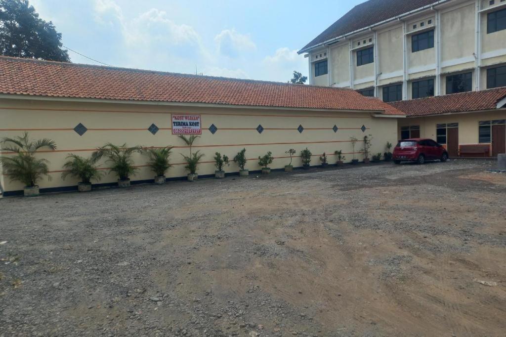 a building with a car parked in front of it at Hotel O Guest House Wijaya Syariah Near alun alun kota purwokerto in Purwokerto
