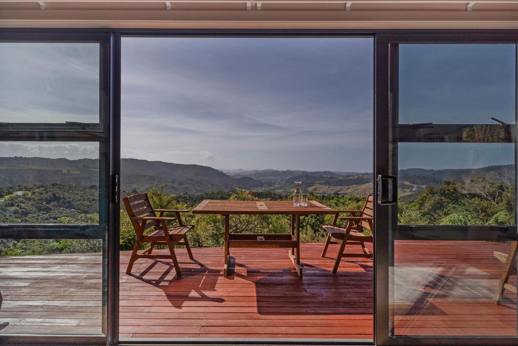 a patio with a table and chairs on a deck at Ridge Valley View in Whenuakite