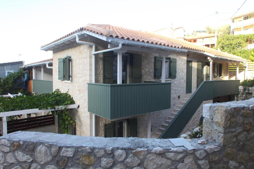 dom z zielonym balkonem przed nim w obiekcie Wild Sea Apartments w mieście Agios Nikitas