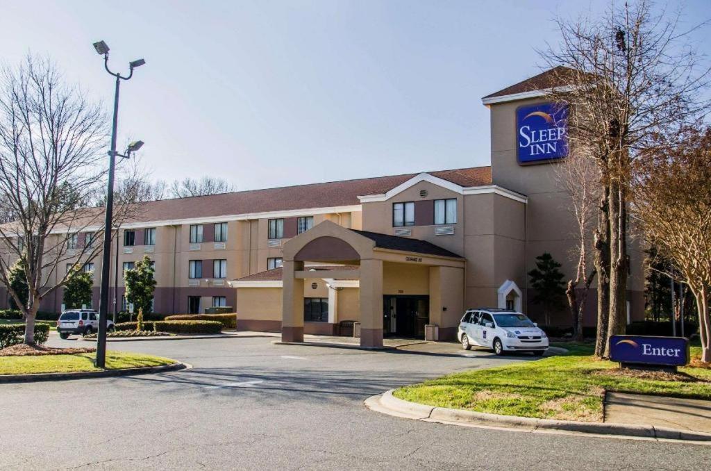 a hotel with a car parked in a parking lot at Sleep Inn Airport - Billy Graham Parkway in Charlotte