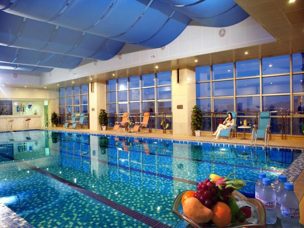 a large swimming pool with a bowl of fruit on a table at Ramada Plaza by Wyndham Hangzhou Riverside in Hangzhou