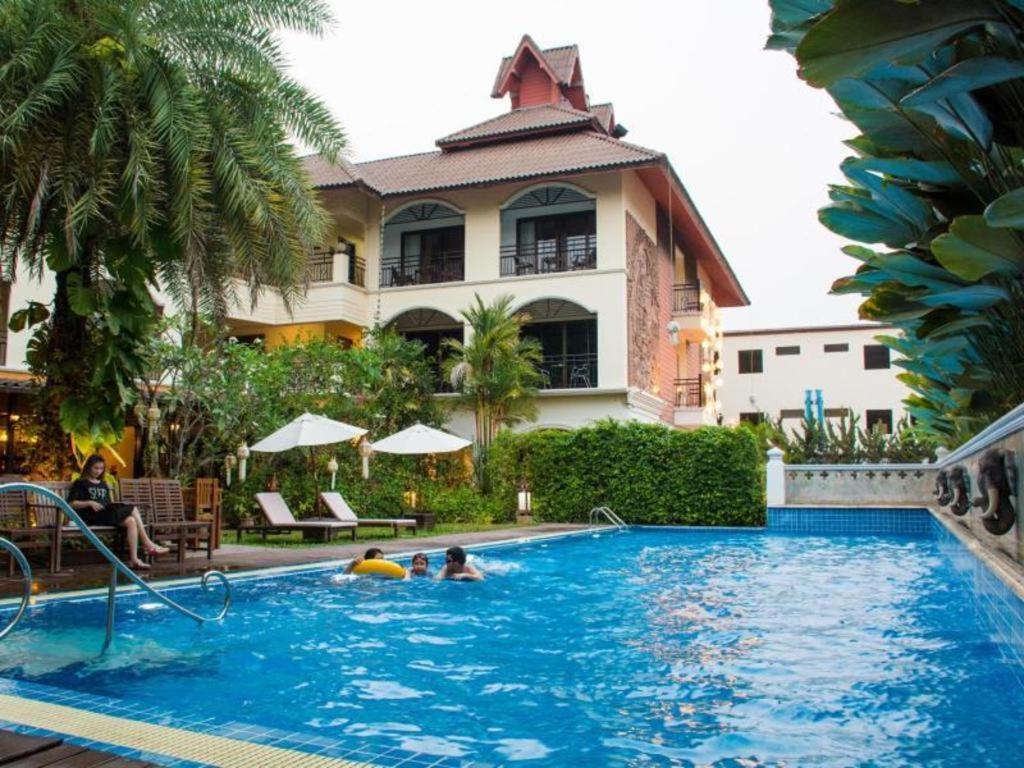 a pool in front of a building with people in it at PhoomThai Garden Hotel in Phrae