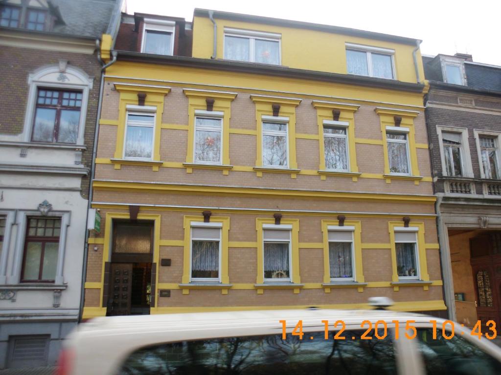 un edificio amarillo con ventanas blancas en una calle de la ciudad en Pension Lehmann en Köthen