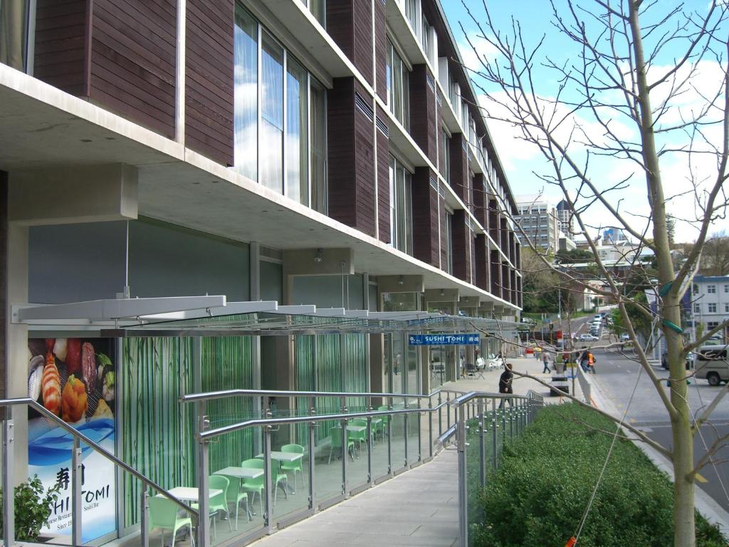 - un bâtiment dans une rue de la ville avec des tables et des chaises dans l'établissement Quest Carlaw Park Serviced Apartments, à Auckland