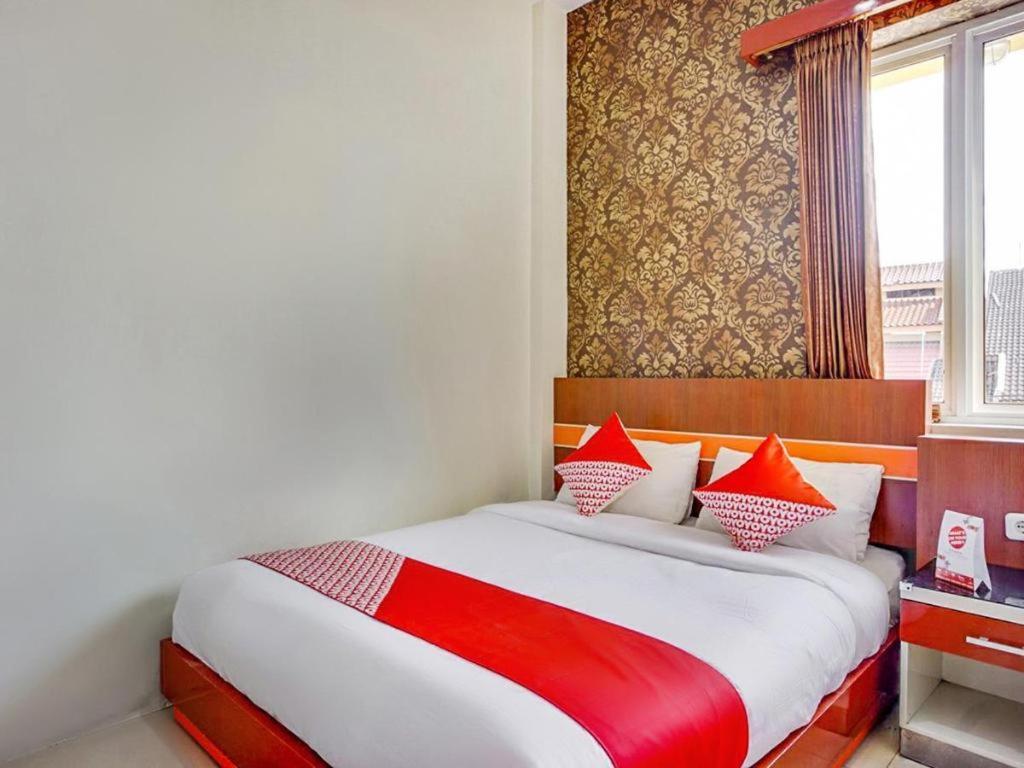 Un dormitorio con una cama grande con almohadas rojas y blancas. en OYO 3157 Grand City Inn, en Pampang