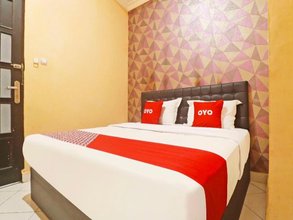 una camera con un letto con due cuscini rossi di Hotel O Papi Inn Guesthouse a Palangkaraya