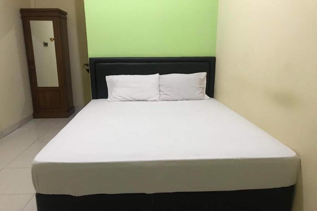 a bed with white sheets and a black headboard in a room at Hotel O Penginapan Mc Lodge in Komodo Labuan Bajo Airport
