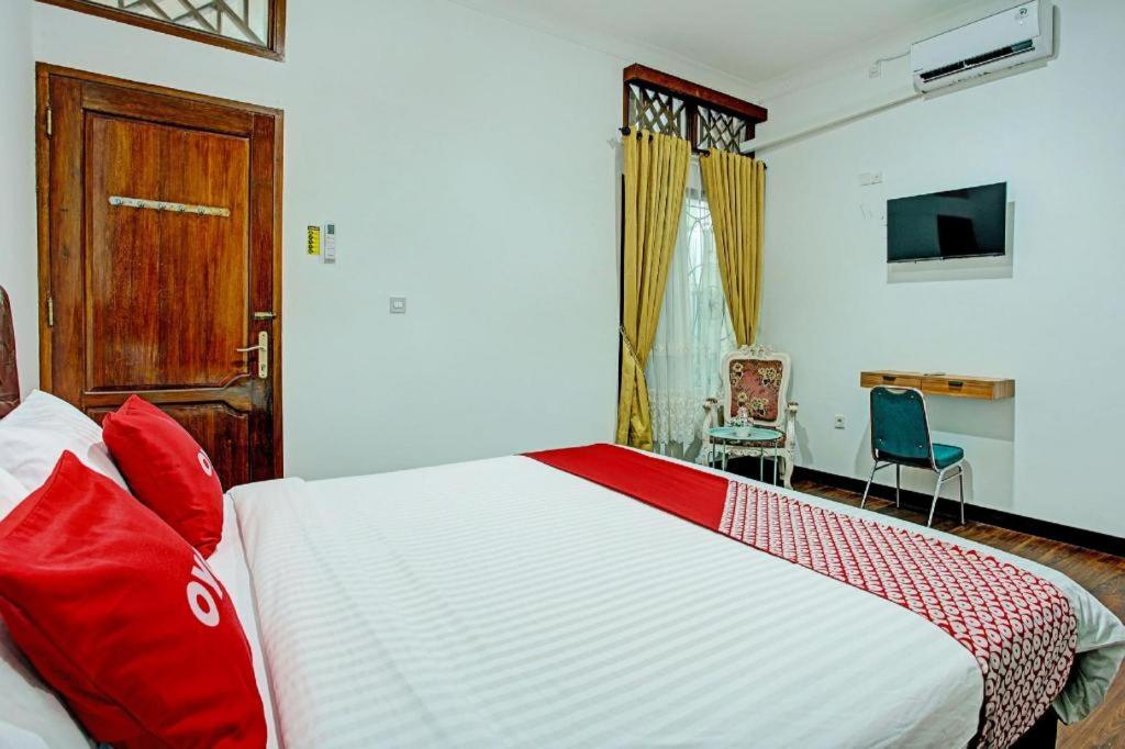 a bedroom with a large bed with red pillows at OYO 92990 Nena Kostel Syariah in Padang