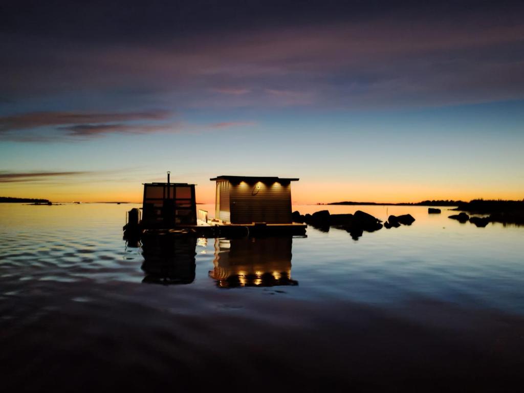 a sunset over a body of water with a house in the water at Mökkilautta in Kalajoki