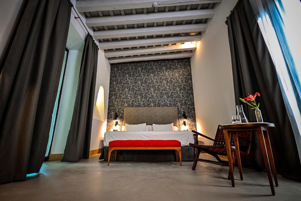 a bedroom with a large bed and a red bench at Hotel Legado Alcazar in Seville