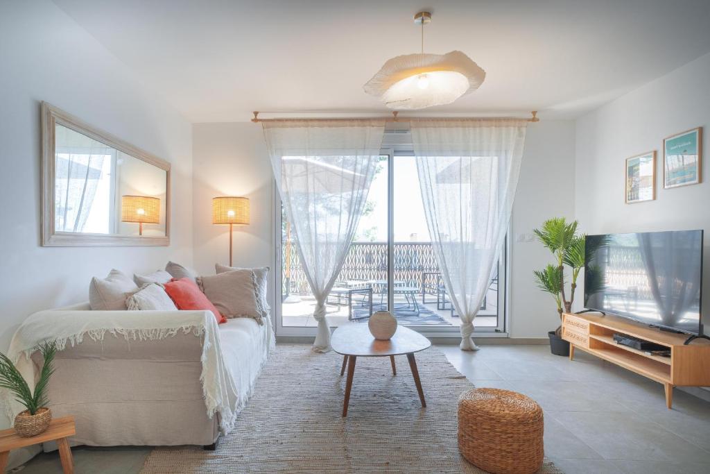 un salon avec un canapé blanc et une télévision dans l'établissement Magnifique appartement niché dans une pinède, à Sanary-sur-Mer