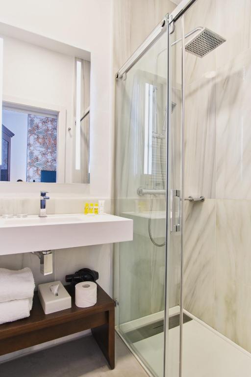 a bathroom with a glass shower and a sink at Hotel Legado Alcazar in Seville