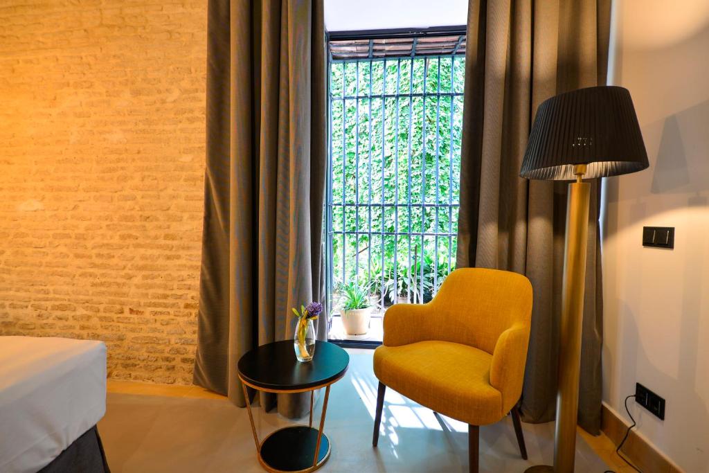 a room with a yellow chair and a window at Hotel Legado Alcazar in Seville