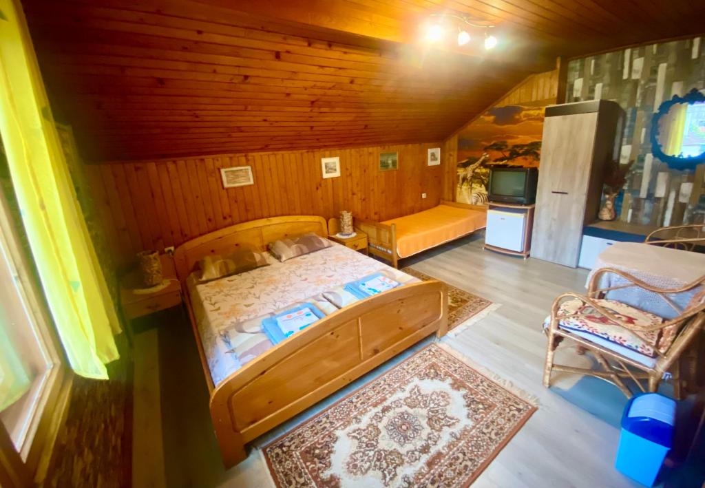 a bedroom with a large wooden bed and a kitchen at Niya Guest House in Beli Iskar