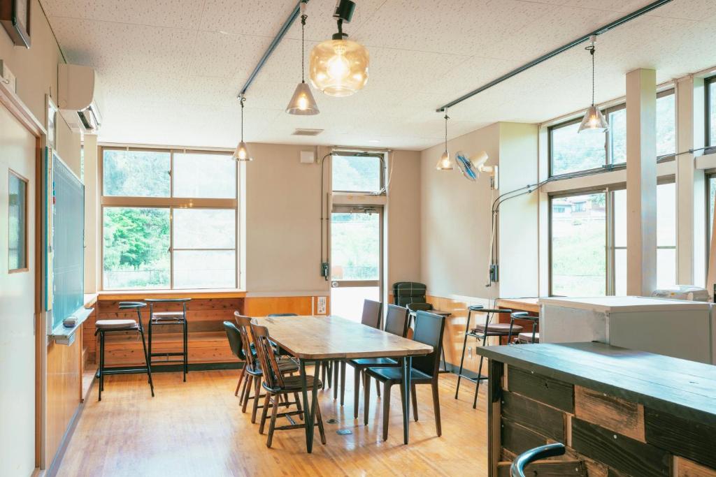a dining room with tables and chairs and windows at まるもりビレッジ in Wada
