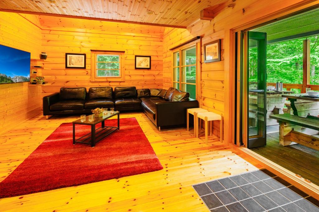 a living room with a black couch and a red rug at Phoenix Chalets by HHG in Hakuba