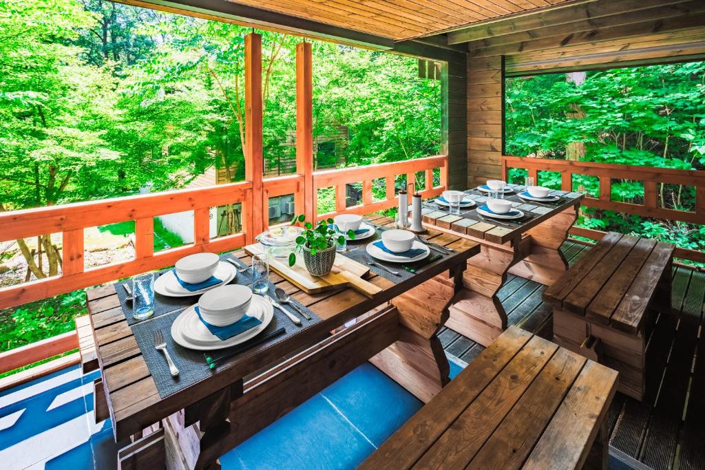 a dining table on the porch of a tree house at Phoenix Chalets by HHG in Hakuba