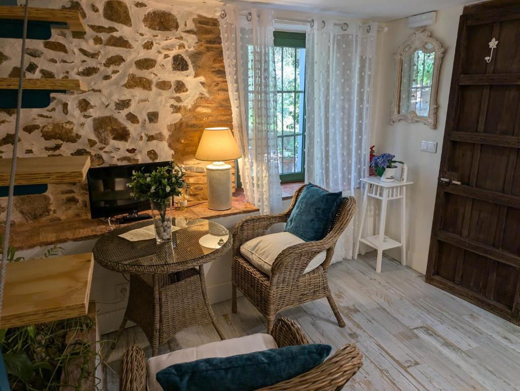 sala de estar con mesa, sillas y pared de piedra en Finca La Favorita- Suites, en Constantina