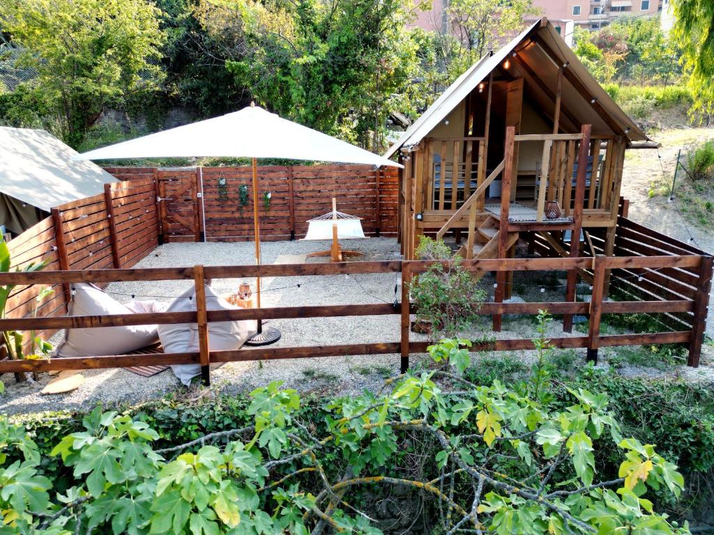 a wooden cabin with an umbrella in a garden at Twiga tenda su palafitta in Imperia