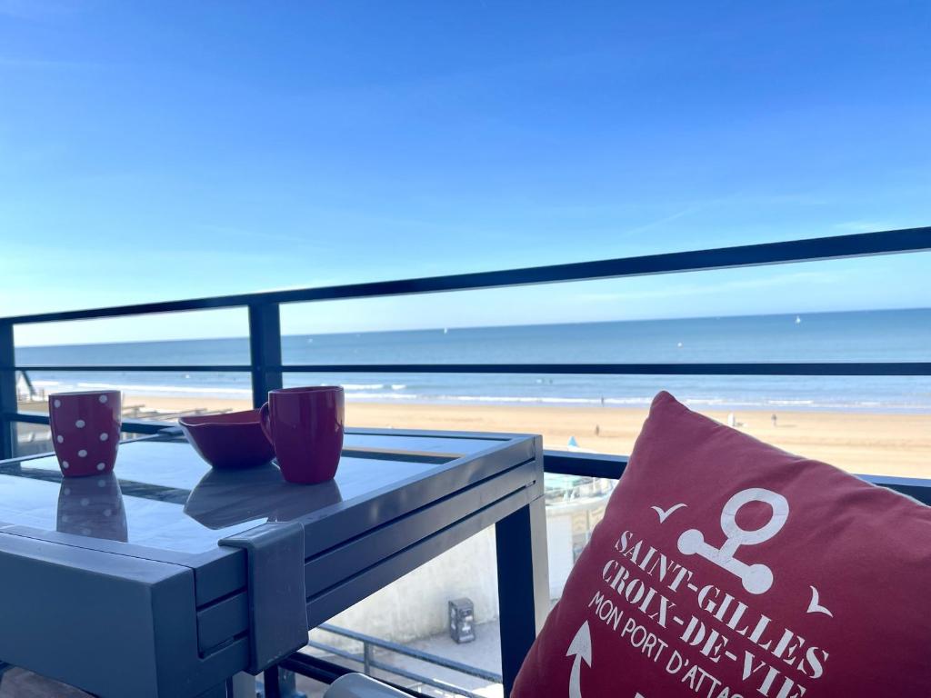 une table sur un balcon avec vue sur la plage dans l'établissement Le Sable doux, à Saint-Gilles-Croix-de-Vie