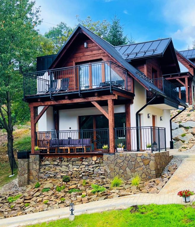 a log house with a balcony on a stone wall at Domki Pienińskie Tarasy in Szczawnica