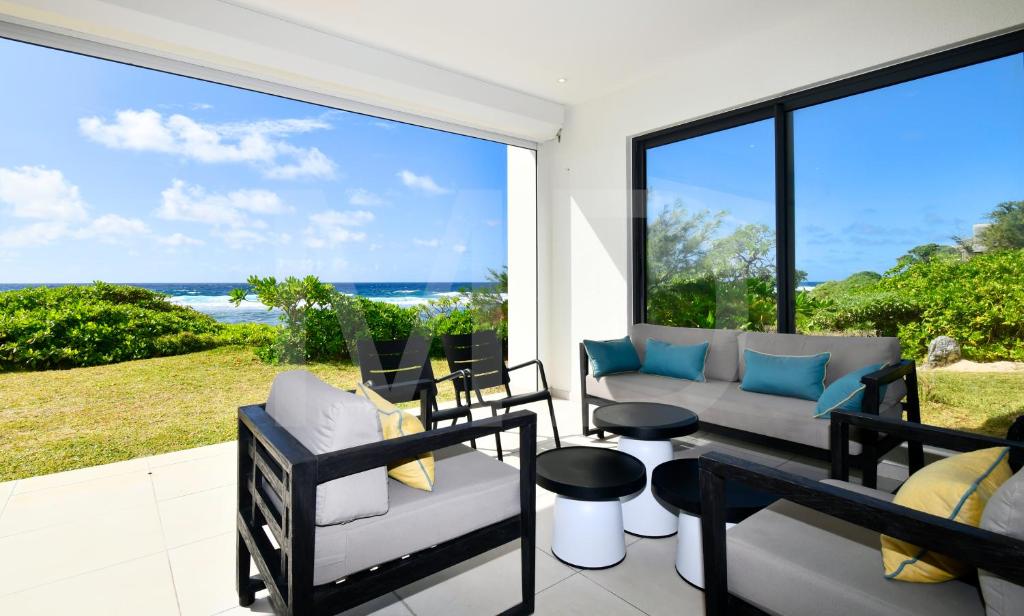 a patio with a couch and chairs and a view of the ocean at White&Blue Beachfront Luxury Poste Lafayette in Poste Lafayette
