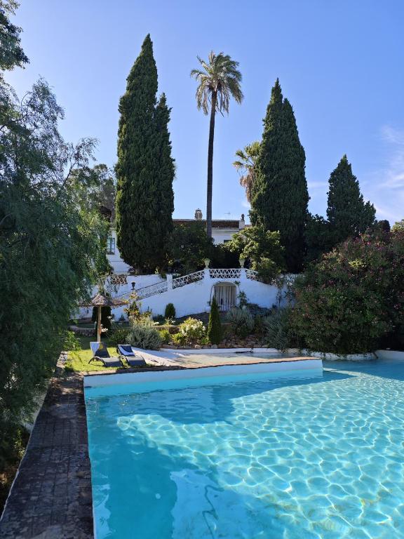 una piscina en un jardín con árboles en Finca La Favorita- Suites, en Constantina