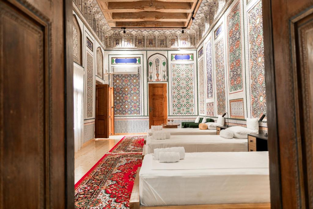 a large room with two beds and a rug at Barlos Noyob in Bukhara