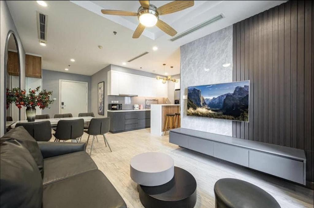 a living room with a couch and a tv on a wall at The RIO Ha Do Home City in Ho Chi Minh City