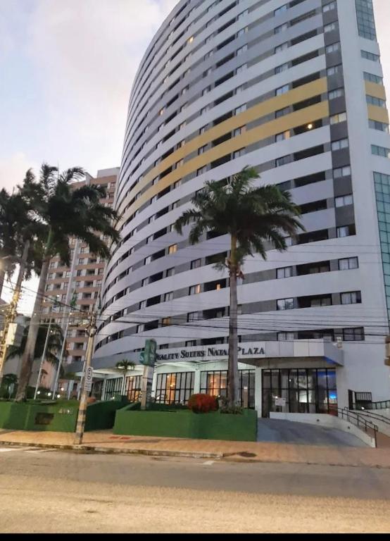 a large building with palm trees in front of it at Hotel Natal Plaza com piscina, academia, 100m da praia de Ponta Neg in Natal