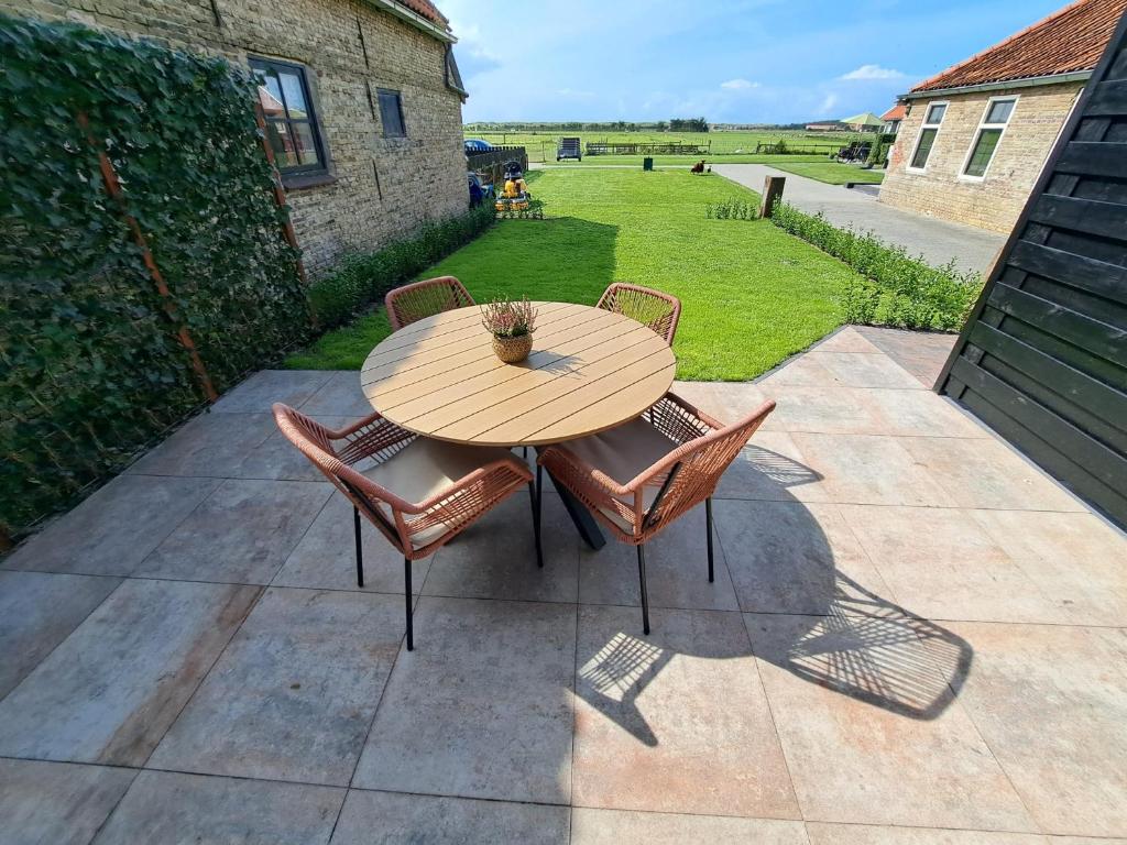 Una mesa y sillas de madera en un patio. en Muziekskuur, en Hollum