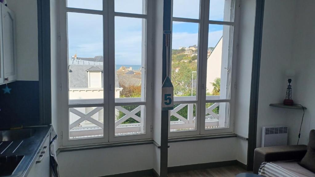 Cette chambre dispose de 3 fenêtres offrant une vue sur l'océan. dans l'établissement Joli Studio vue mer 200 m de la plage, à Pléneuf-Val-André