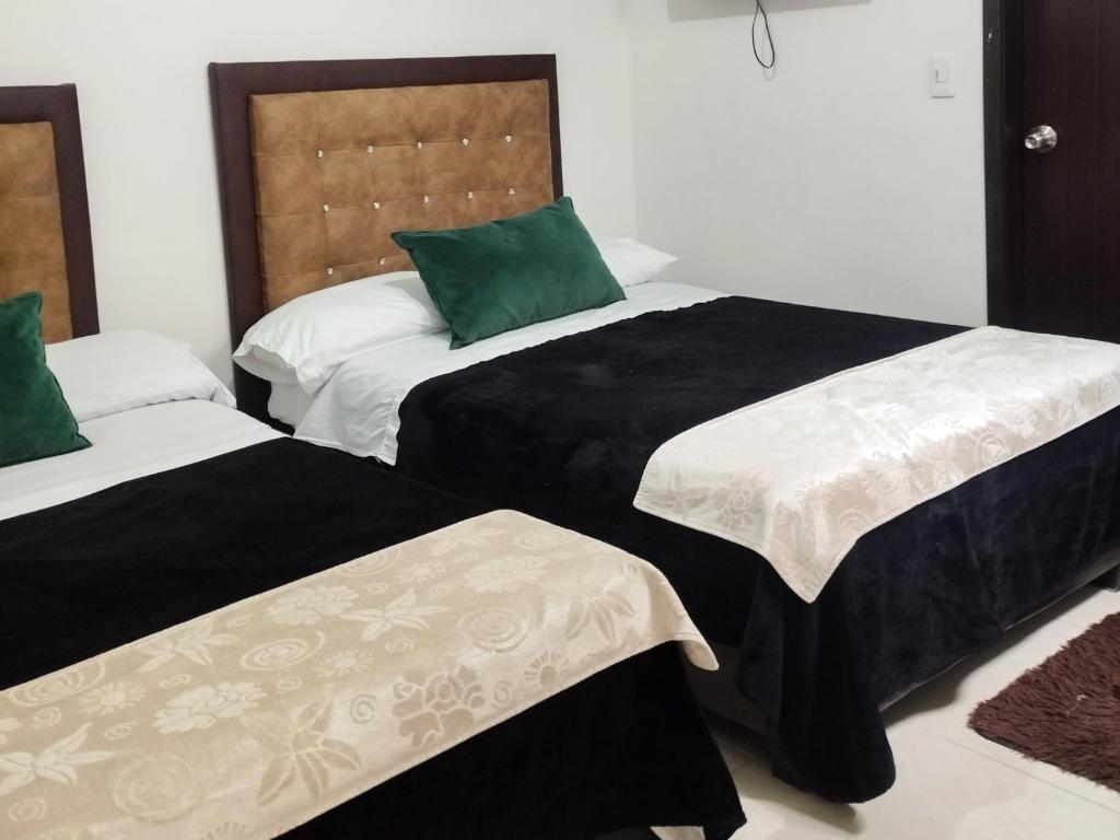 1 Schlafzimmer mit 2 Betten in Schwarz und Weiß in der Unterkunft Hotel Guadalupe Home in Pereira